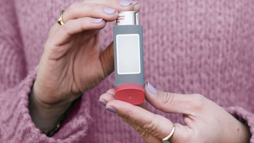 Hands holding an asthma inhaler.