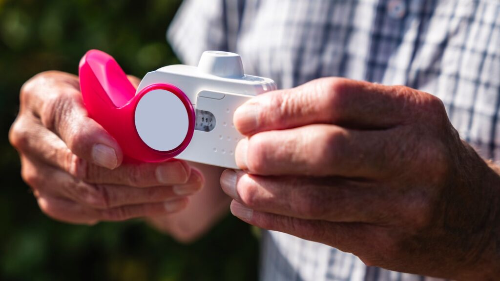 An older adult holding an inhaler in both hands.