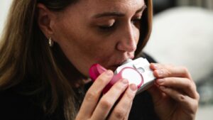 A woman using an inhaler, one of the everyday treatments for asthma.