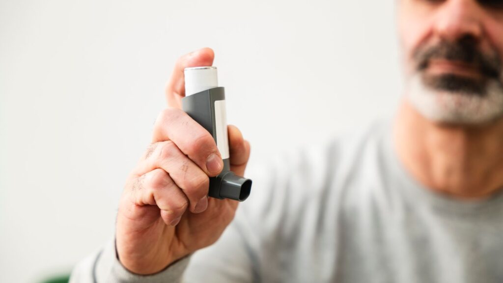 A middle-aged man holding an inhaler.