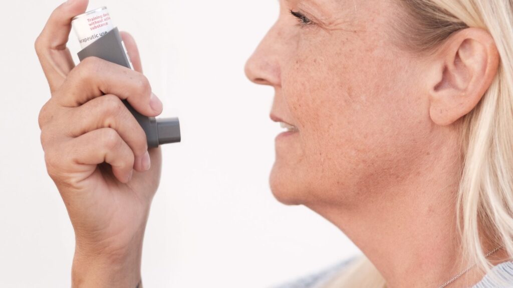 A woman holding an inhaler up to her mouth.